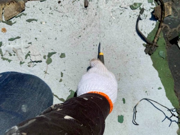 カッターで古い防水に切り込みを入れている