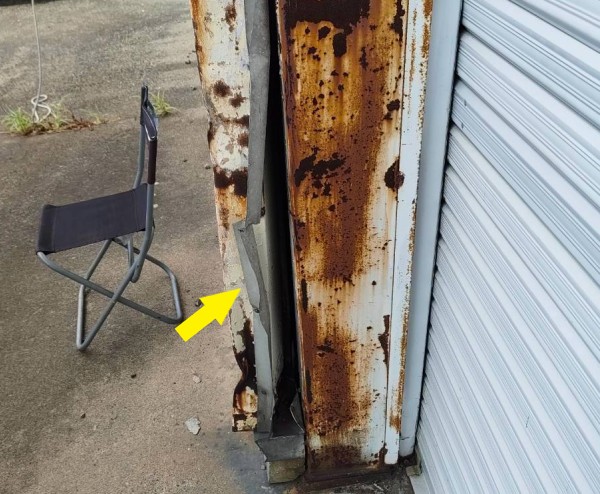 倉庫のシャッター横の板金が歪んでいる