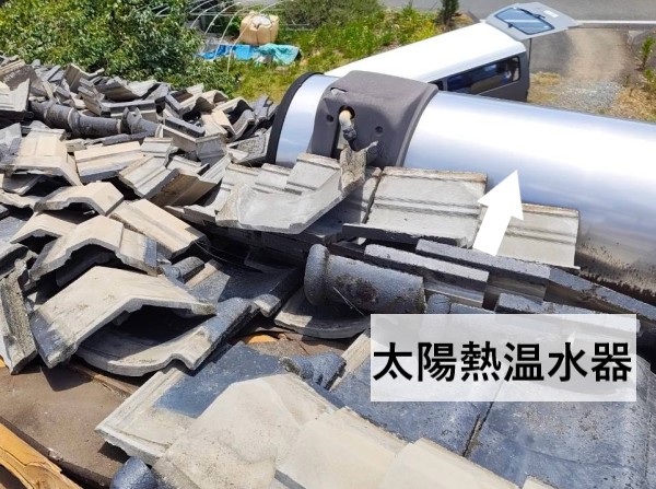 地震で瓦がズレた屋根に太陽熱温水器が載っている
