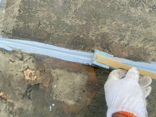 屋上の目地シーリングをヘラで均します