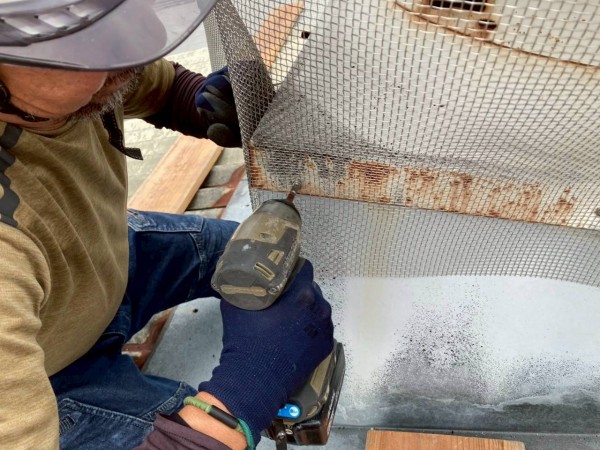 屋根上の換気扇にも防虫網を取り付けている様子