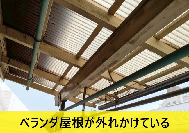 木造のベランダで波板屋根が外れかけている