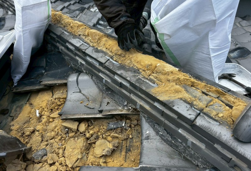 瓦と葺き土を撤去して土嚢袋に入れている